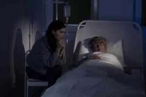 badante notturna che assiste un anziano in ospedale