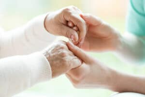 mani di anziana e badante che si toccano