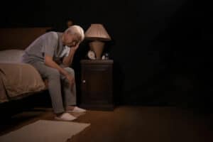 anziano che soffre di insonnia seduto sul letto
