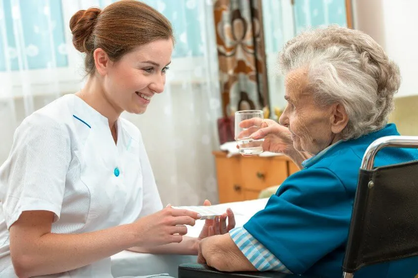 badante qualificata che somministra medicine all'assistita