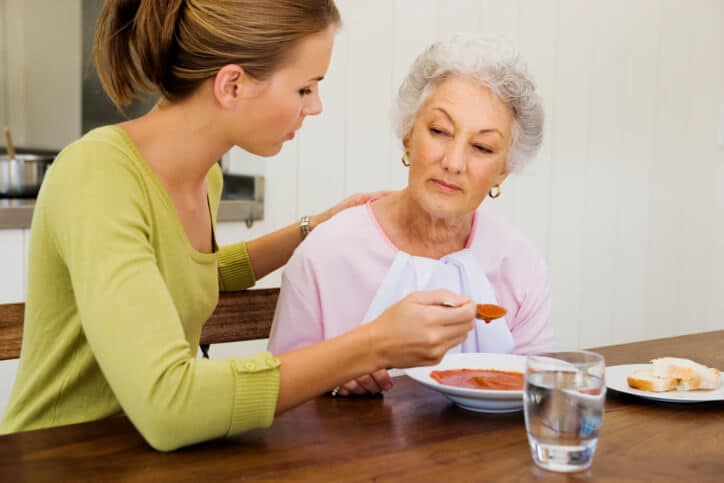 badante che aiuta anziana con i pasti