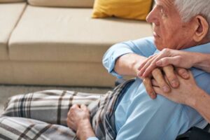 anziano in sedia a rotelle che stringe la mano della badante